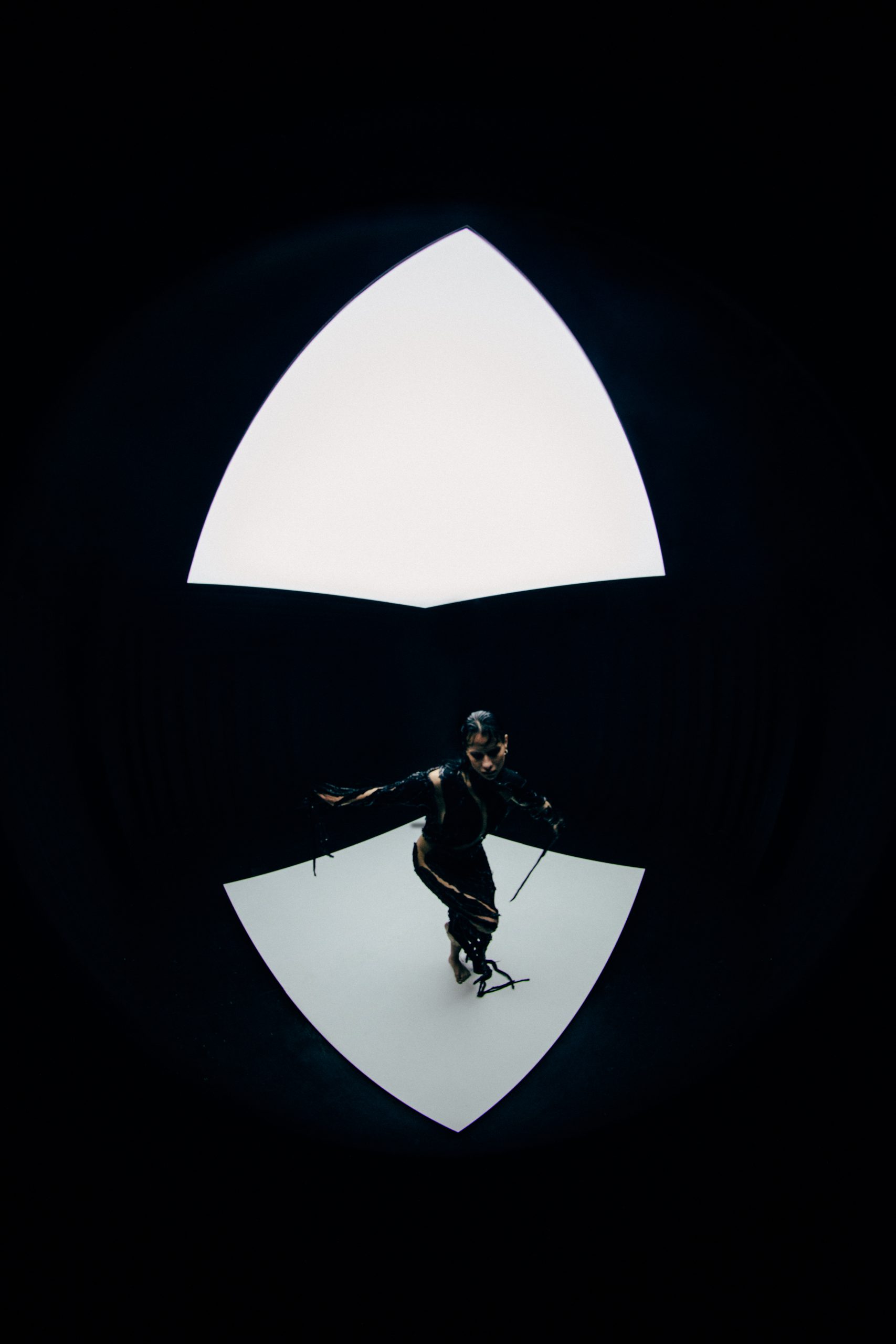 full body fisheye image of mdoel wearing skin tight black cutout dress looking downward