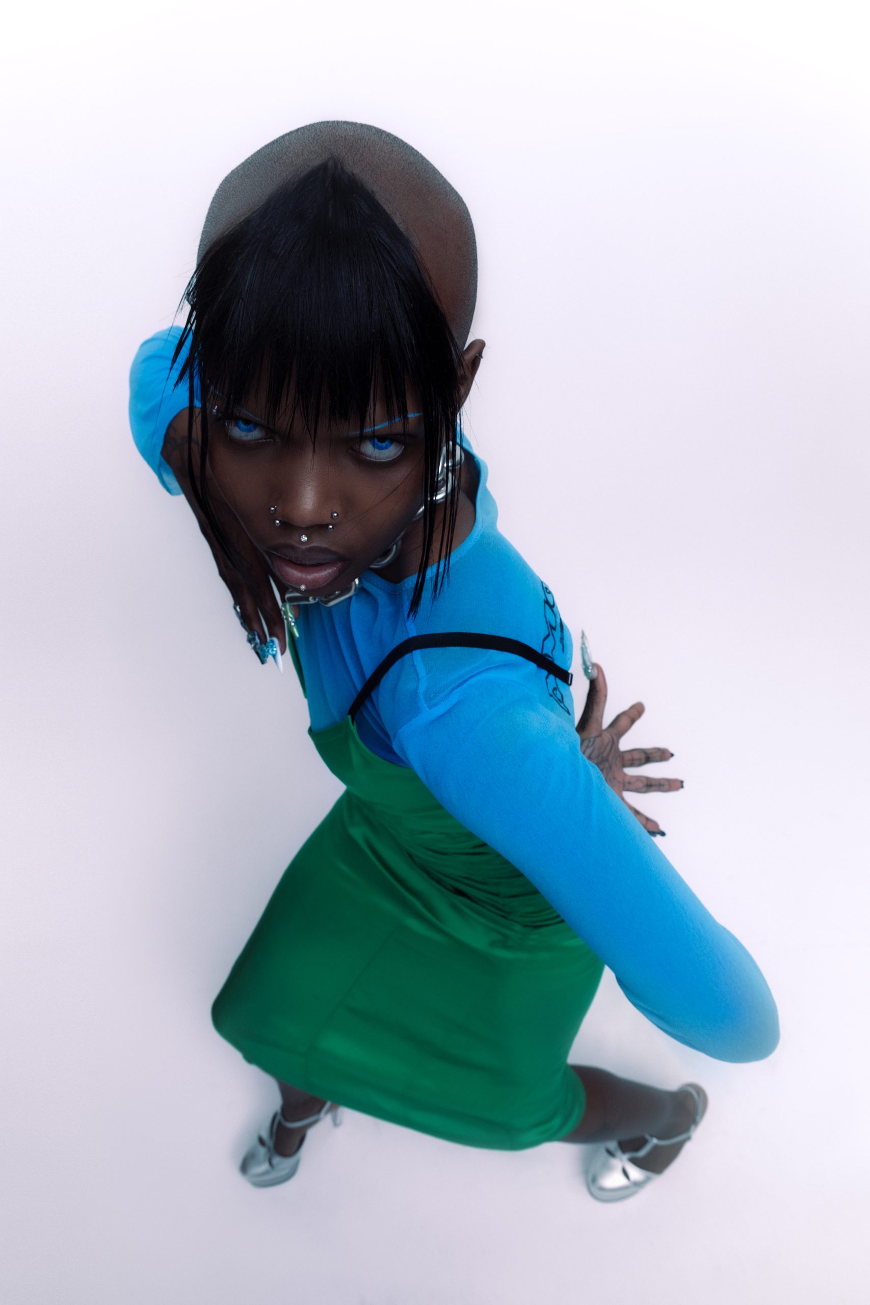 wide angle shot from above of black bald model dressed in blue green in silver