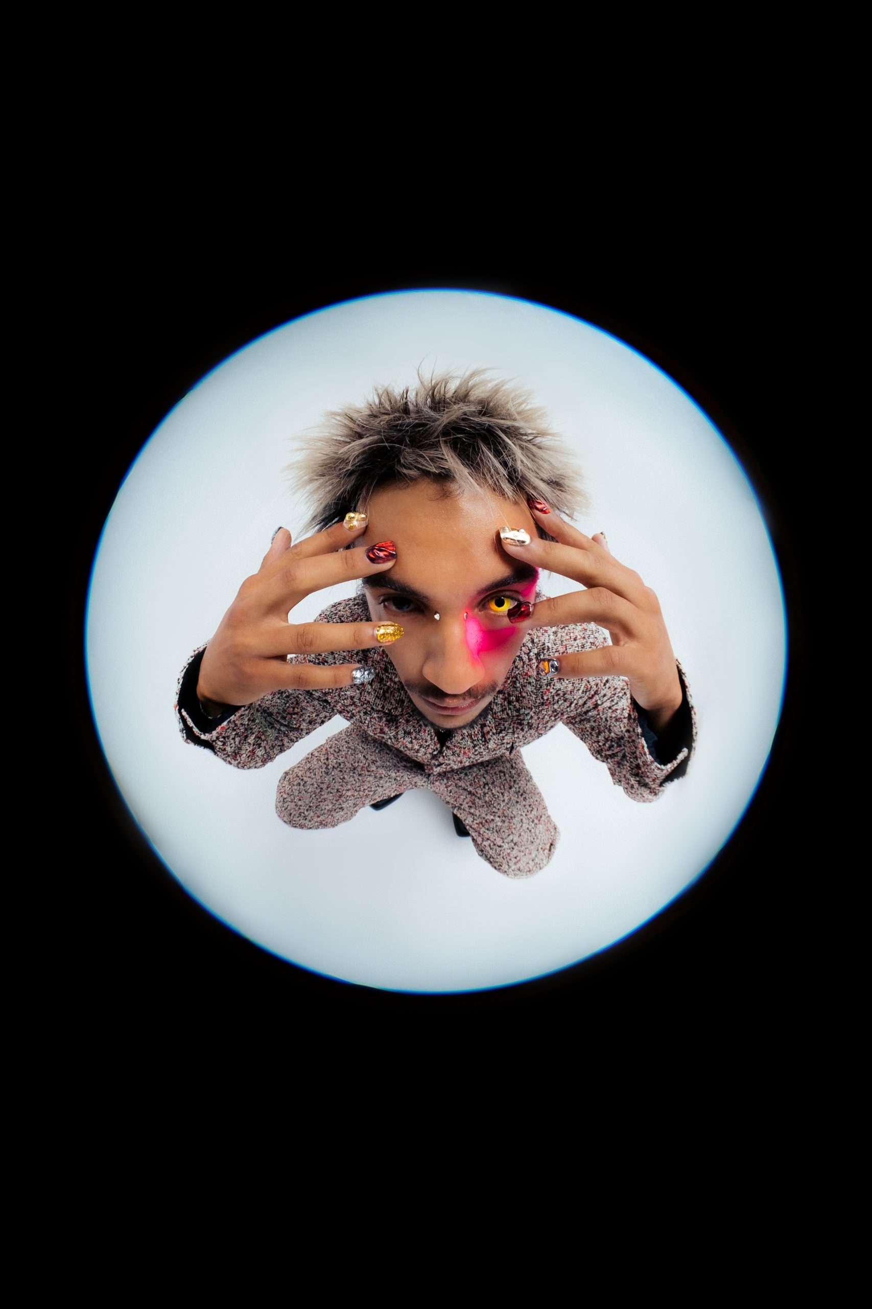 Fisheye closeup shot of black male model dressed in dotted colorful look with colorful nails