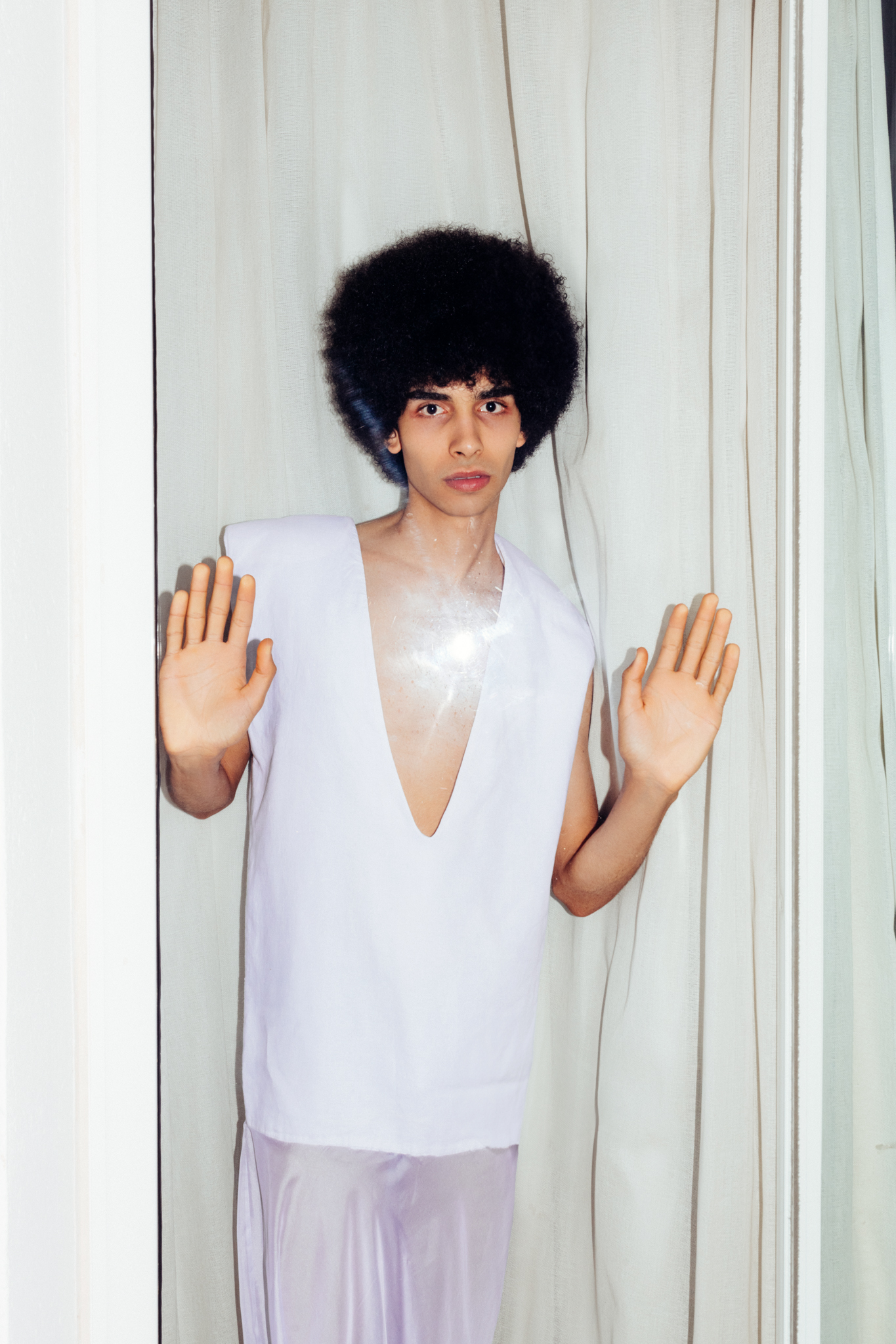 Yassin Walhezi a male tunisian model with an afro is wearing a white dress by Souraya Sahraoui, photographed by Frederik Wetzels.