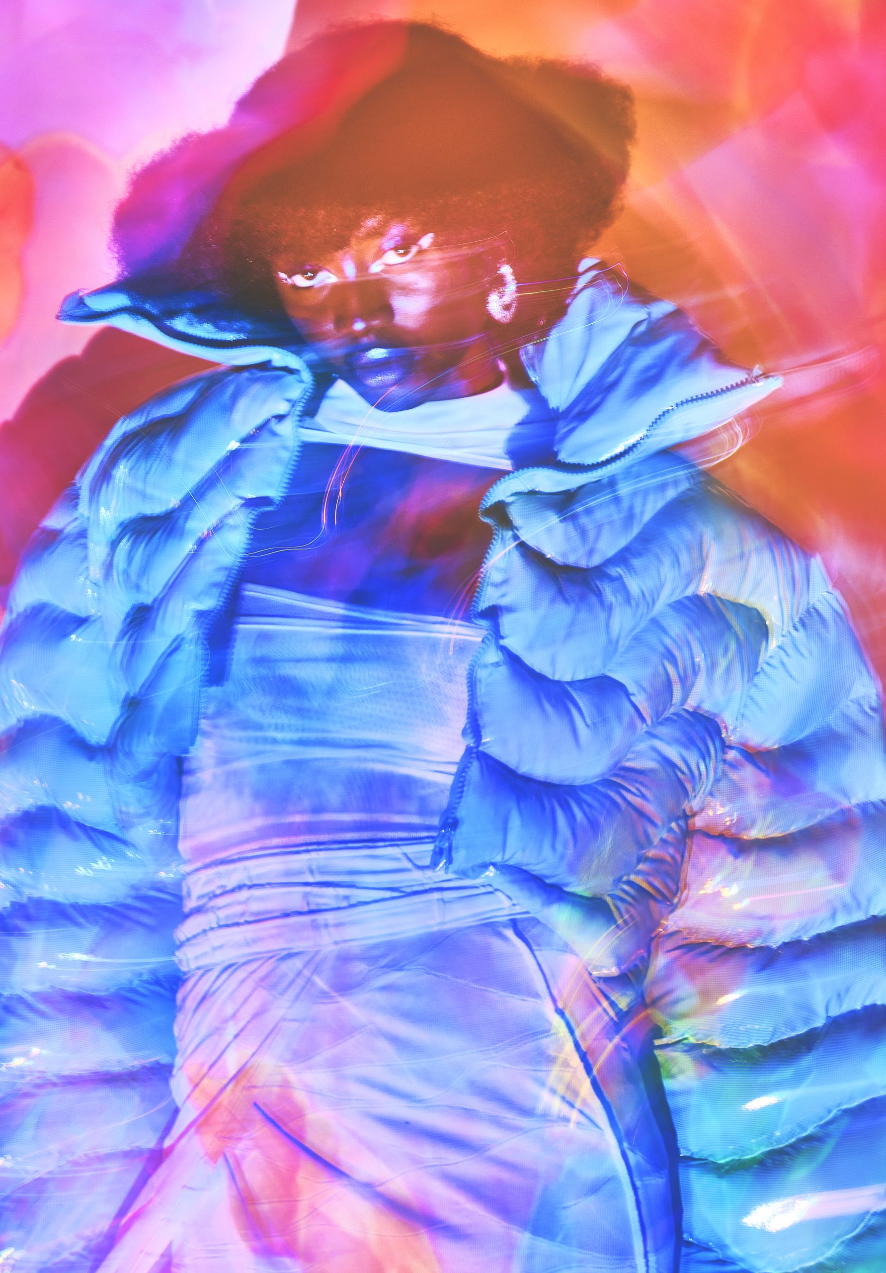 Three quarter shot of black model in puffer jacket and dress shot with slow shutter and colorful